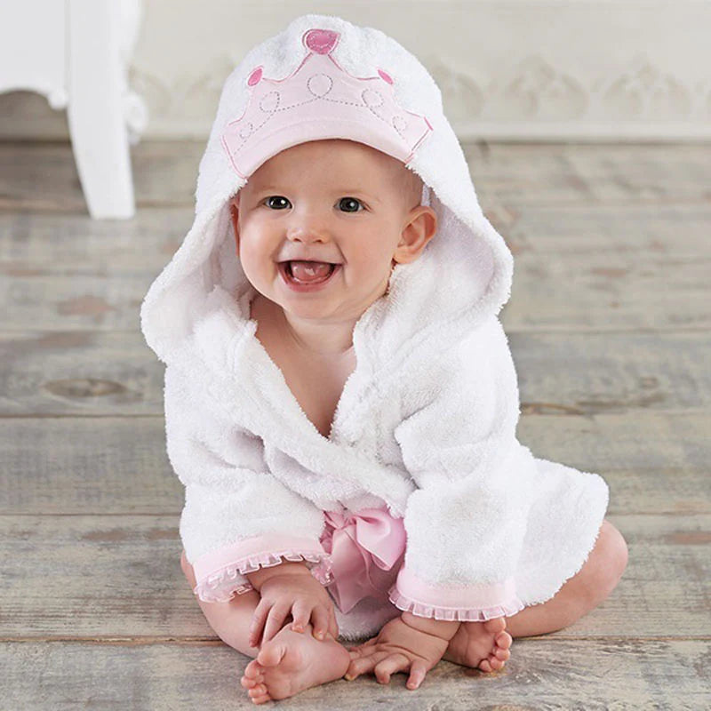 Smiling baby wearing a white hooded towel with pink accents.